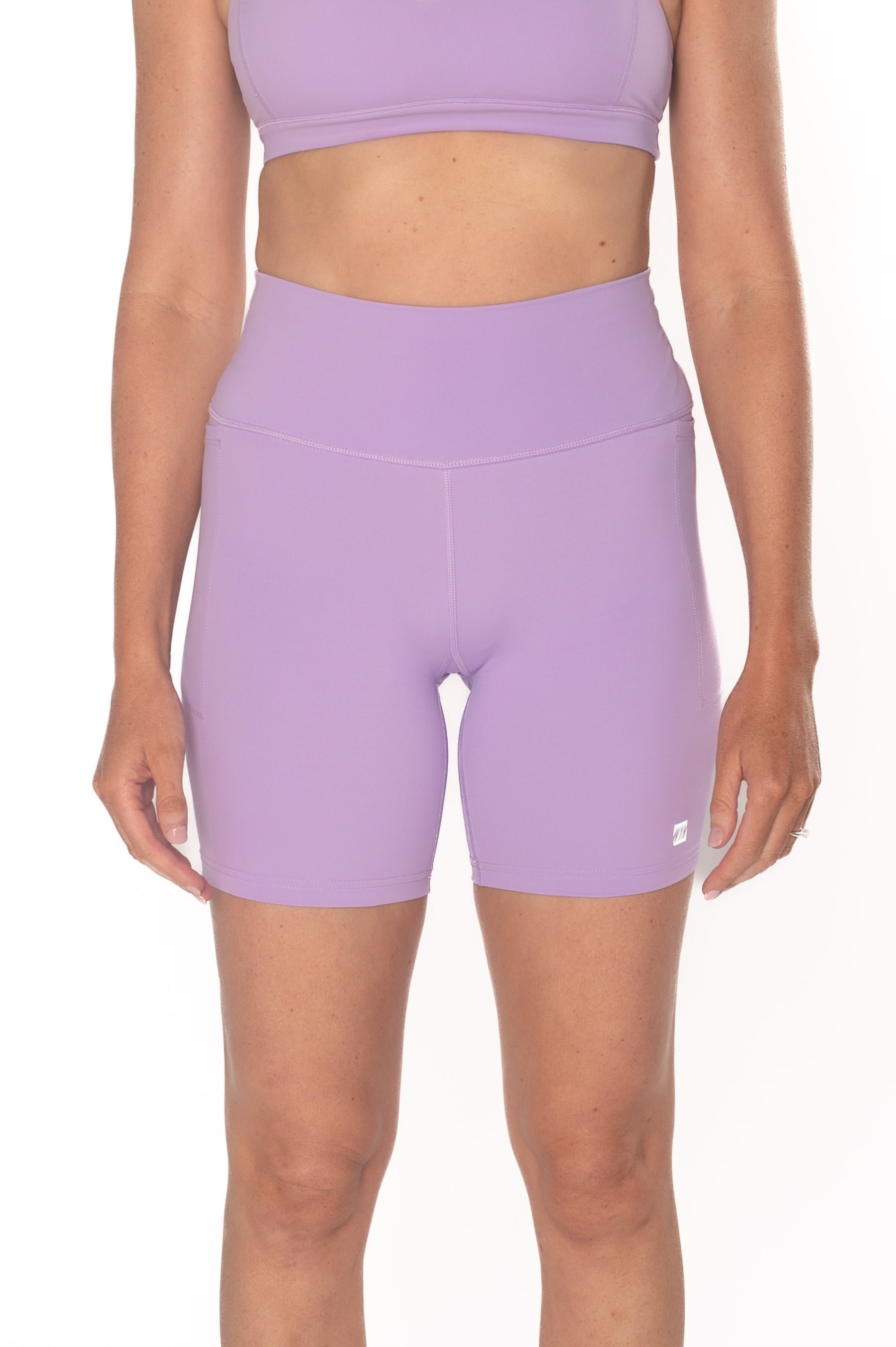 Person wearing a purple sports bra and shorts set on a white background