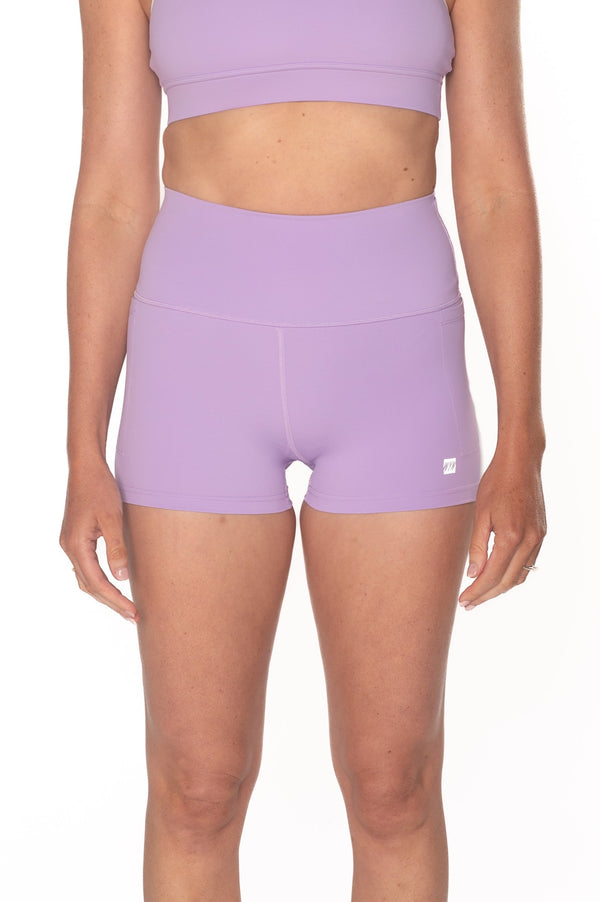 Person wearing a purple sports bra and shorts set on a white background