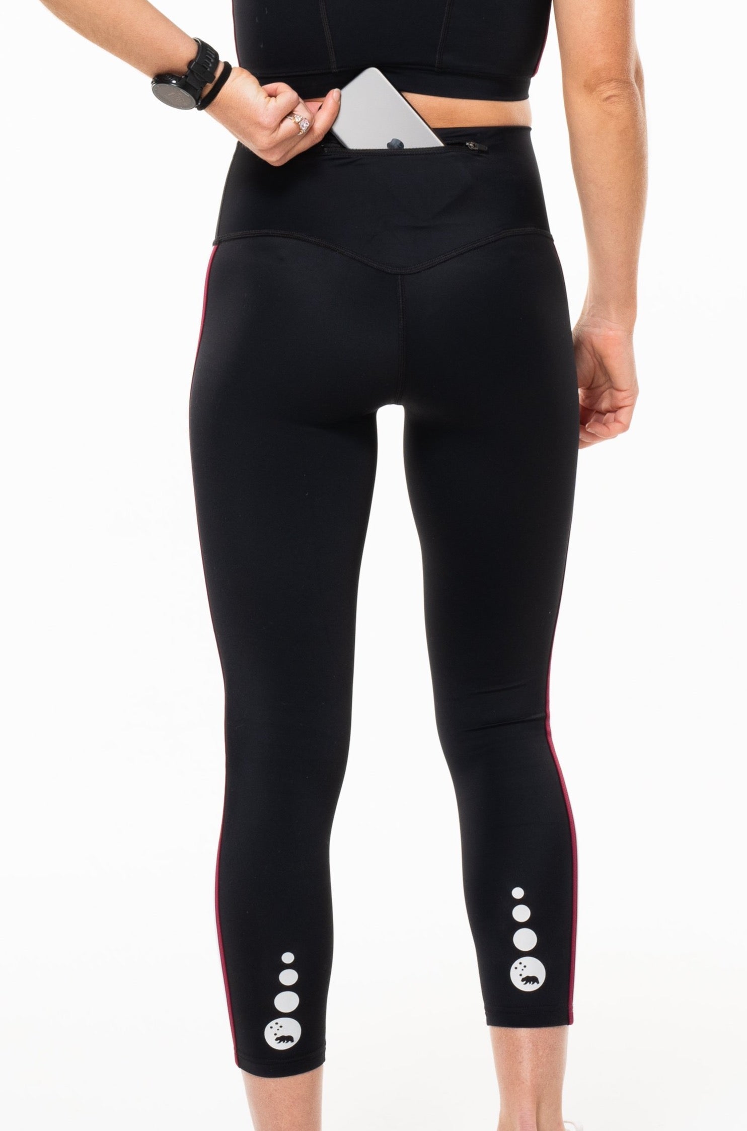 Model placing a phone in Strata 7/8 leggings. Leggings with zipper pocket on waistline.