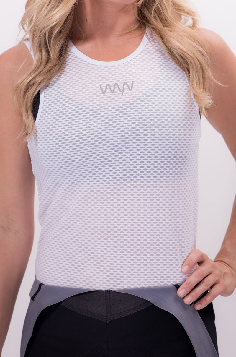 Model wearing WYN republic Women's Sleveless Base Layer. White cycling base layer with reflective logo.