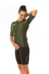 Model wearing women's mocha Velocity Cycling Bib Shorts with green jersey. Fast cycling kit.