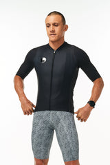 Model wearing men's onyx Hex Racer Jersey with WYN republic Snow Leopard Bib Shorts. Bold cycling kit.