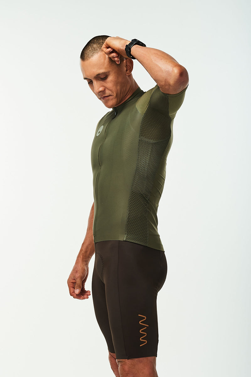 Model lifting left arm of men's Hex Racer Jersey. Flexible Green cycling jersey with mesh panels.