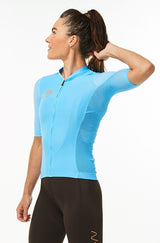 Model lifting left arm of women's Hex Racer Jersey. Flexible blue cycling jersey with mesh panels.