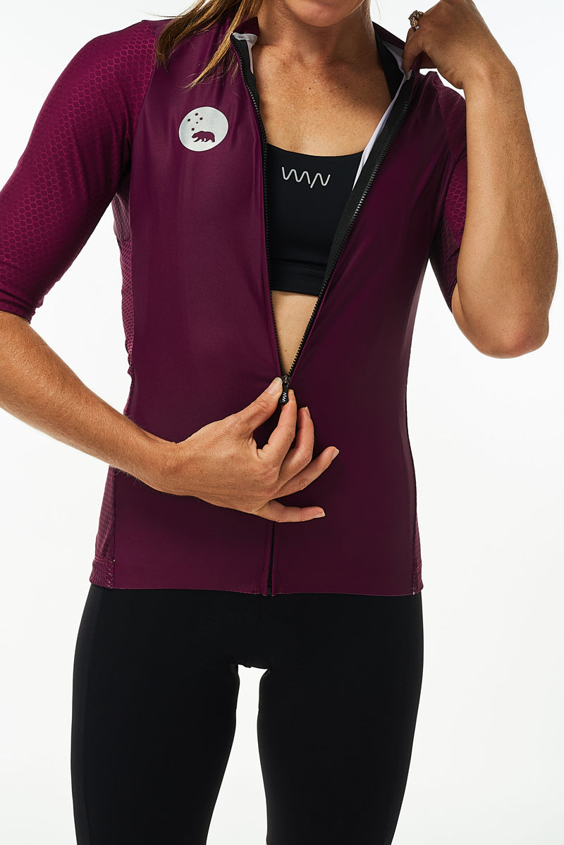 Model zipping women's Tyrian Hex Racer Jersey. Purple cycling jersey with flip-lock zipper.