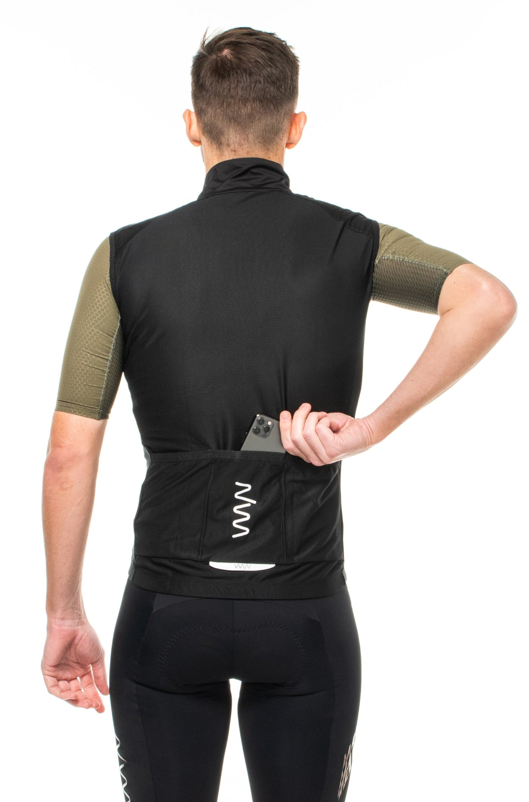 Model placing a phone in back pocket of men's black gilet. Black wind vest with storage.